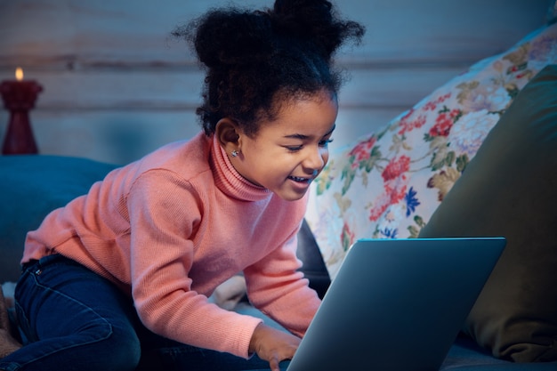 Gelukkig afrikaans-amerikaans meisje tijdens videogesprek met laptop en thuisapparaten