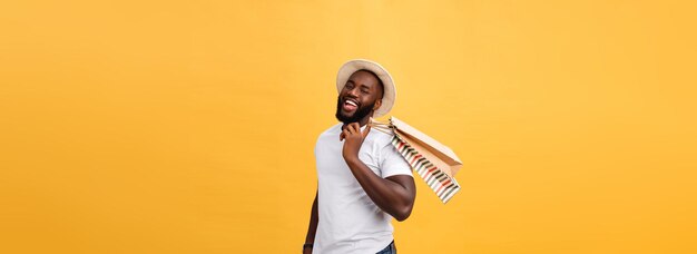 Gelukkig Afro-Amerikaanse man met boodschappentassen op gele achtergrond vakantie concept