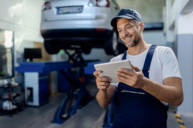 Gelukkig auto reparateur bezig met touchpad in een werkplaats