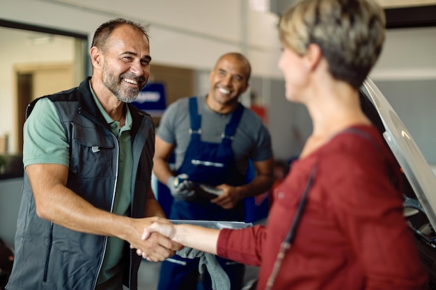 Gratis foto gelukkig autoreparateur handenschudden met klant in een werkplaats