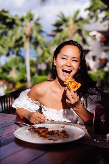 Gelukkig Aziatische mooie vrouw hongerig met pizza op zonnige dag zonsondergang licht in openluchtrestaurant Vrouw genieten van eten met plezier tijdens de lunch