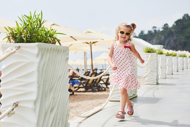 Gelukkig babymeisje in een jurk op het strand aan zee in de zomer.