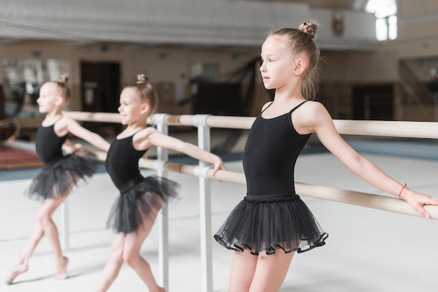 Gelukkig ballerinameisje die bij barre met haar vrienden uitoefenen