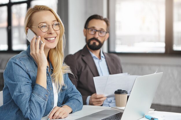 Gelukkig blonde vrouwelijke manager heeft gesprek met mannelijke collega