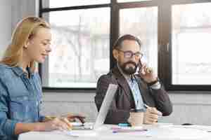 Gratis foto gelukkig blonde vrouwelijke manager heeft gesprek met mannelijke collega