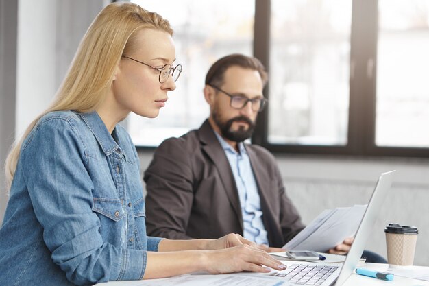 Gelukkig blonde vrouwelijke manager heeft gesprek met mannelijke collega