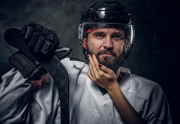 Gelukkig brutale hockeyspeler poseert voor fotograaf terwijl vrouw met nauwkeurige manicure hem aanraakt.