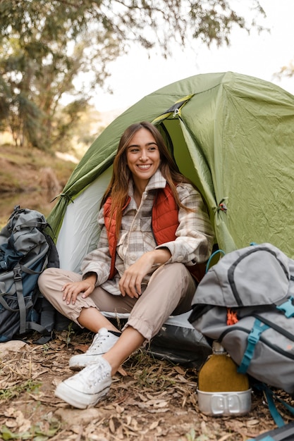 Gelukkig camping meisje in het bos, zittend in de tent