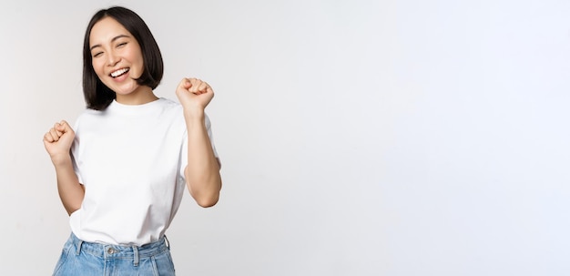 Gelukkig dansend Koreaans meisje poseren tegen een witte achtergrond met tshirt