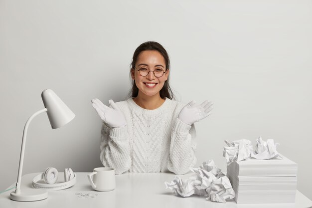 Gelukkig donkerharige vrouw administratief manager draagt nette witte trui en handschoenen