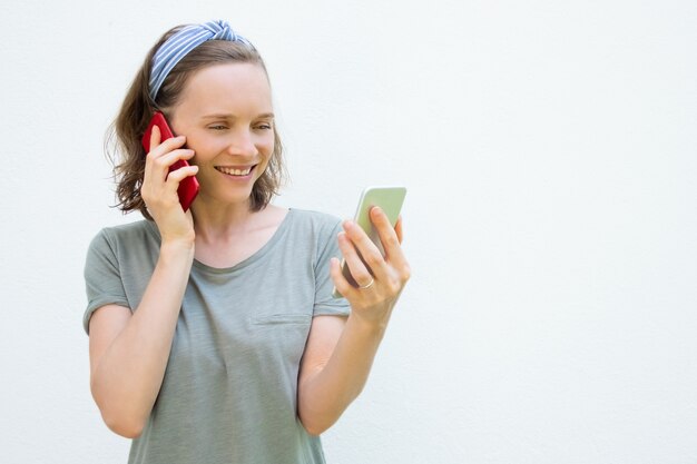 Gelukkig drukke jonge vrouw met behulp van twee mobiele telefoons
