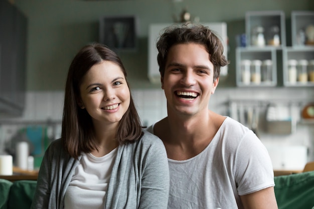 Gelukkig duizendjarig paar die camera in keuken, headshotportret bekijken