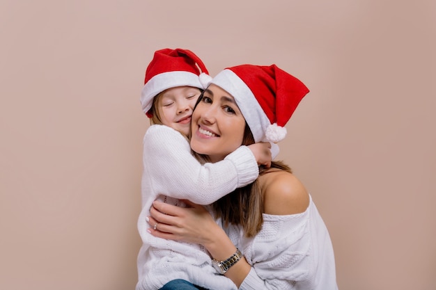 Gelukkig familieportret van schattige moeder met dochter kerstfeest dragen santa caps.