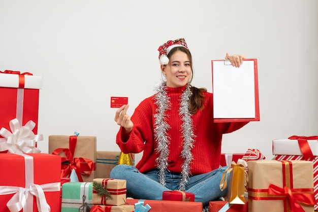 gelukkig feest meisje met kerstmuts bedrijf kaart en documenten rondhangen presenteert op wit