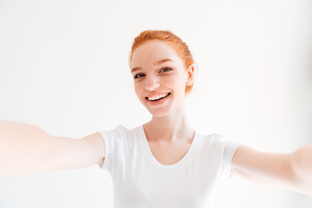 Gelukkig gember vrouw in t-shirt selfie maken en kijken