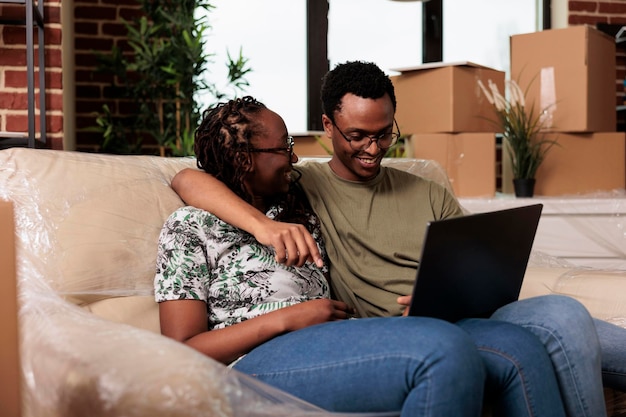 Gelukkig getrouwd stel vindt meubels op online website, winkelt op laptop om gehuurde flat te versieren. Decoraties kopen via internetbrowser na verhuizing naar een nieuw huis.