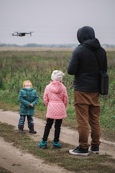 Gelukkig gezin met twee kinderen spelen met drone in het veld herfsttijd.