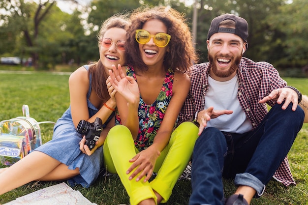 Gelukkig jong gezelschap van pratende lachende vrienden zitten park, man en vrouw samen plezier hebben, reizen met camera