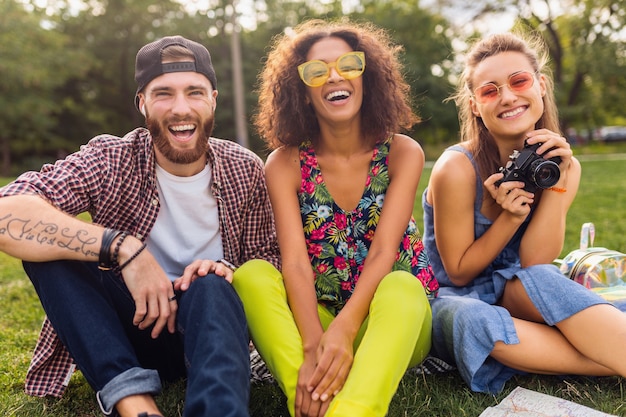 Gelukkig jong gezelschap van vrienden die in het park zitten, man en vrouw die samen plezier hebben, reizen met camera,