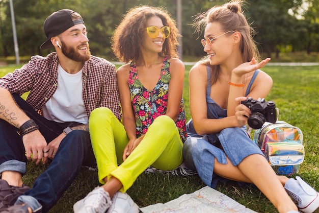 Gelukkig jong gezelschap van vrienden zitten park, man en vrouw samen plezier, kleurrijke zomer hipster fashion stijl, reizen met camera, praten, glimlachen