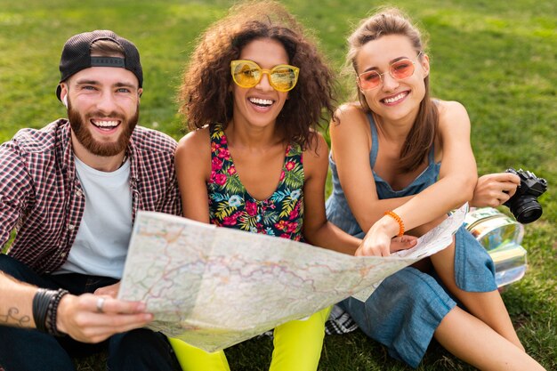 Gelukkig jong gezelschap van vrienden zitten park reizen op zoek in kaart bezienswaardigheden, man en vrouw samen plezier