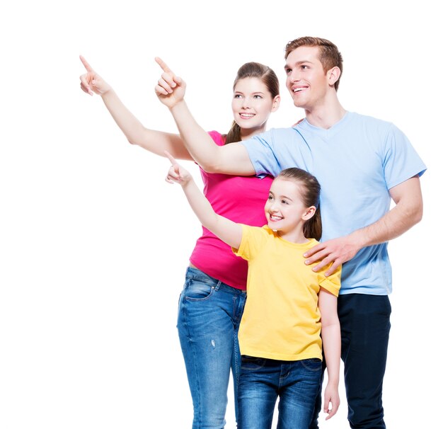 Gelukkig jong gezin met kind wijzende vinger - geïsoleerd op een witte muur