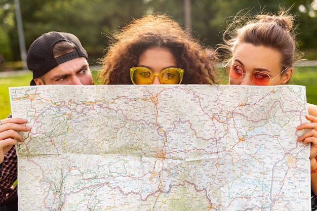 Gelukkig jong grappig gezelschap van vrienden toeristen verstopt achter kaart in zonnebril, man en vrouw samen plezier hebben, reizen