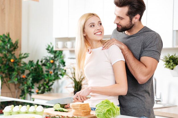 Gelukkig jong houdend van paar die zich bij keuken en het koken bevinden