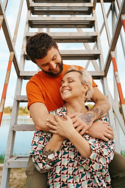 Gratis foto gelukkig jong koppel knuffelen en lachen buiten op trappen