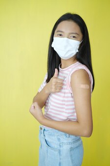 Gelukkig jong meisje draagt een masker met schouder na vaccinatie.