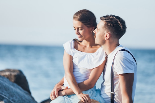 Gelukkig jong romantisch paar die op het strand ontspannen en op de zonsondergang letten