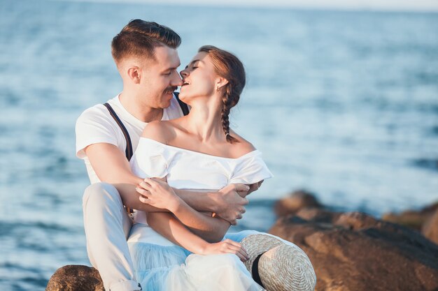 Gelukkig jong romantisch paar die op het strand ontspannen en op de zonsondergang letten