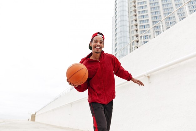 Gelukkig jonge Afrikaanse man lopen spelen basketbal.