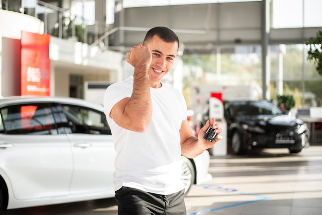 Gratis foto gelukkig jonge man bij autodealer