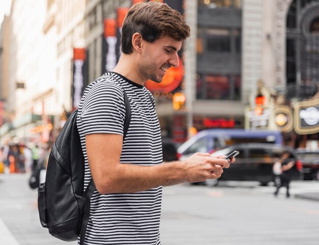 Gelukkig jonge man te typen op een smartphone