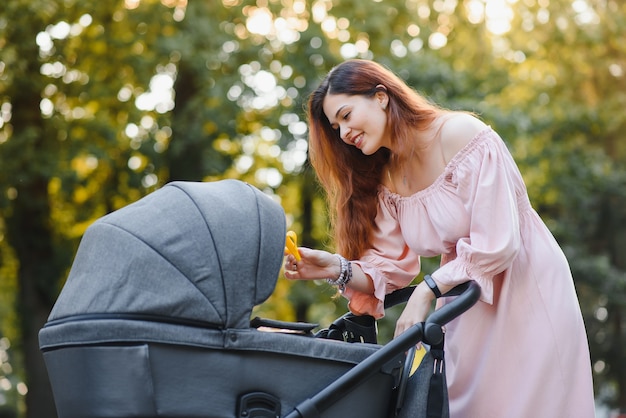 Gelukkig jonge moeder met baby in buggy wandelen in herfst park