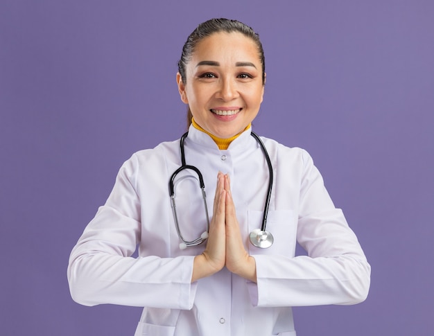 Gelukkig jonge vrouw arts hand in hand samen als namaste gebaar glimlachen