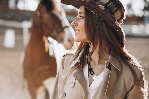 Gratis foto gelukkig jongedame met paard op ranch