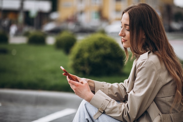 Gelukkig jongedame zitten in het park en praten over de telefoon