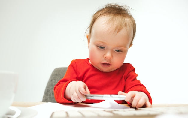 Gelukkig kind babymeisje peuterzitting met toetsenbord van computer geïsoleerd op een witte achtergrond