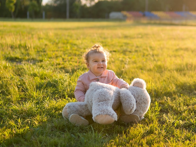 Gelukkig kind in roze kleding en teddybeer