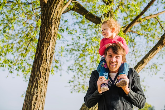 Gratis foto gelukkig kind op de schouders van zijn vader