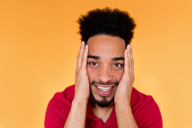 Gelukkig knappe afro Amerikaanse man met rode t-shirt glimlachend over oranje muur.