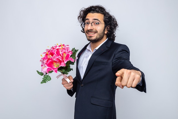 Gelukkig knappe man in pak met boeket bloemen glimlachend vrolijk wijzend met wijsvinger