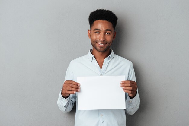 Gelukkig lachend Afrikaanse man met blanco vel papier