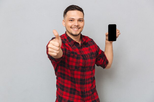 Gelukkig lachend casual man met leeg scherm mobiele telefoon