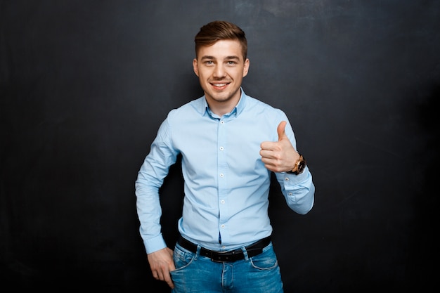 gelukkig lachend jonge man in blauw shirt over schoolbord thumbs up