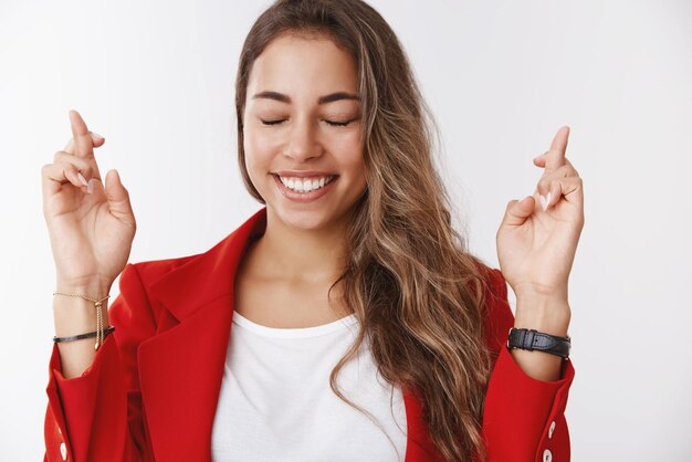 Gratis foto gelukkig lachend prachtige 25s blanke vrouw die god vraagt, wens laten uitkomen, gelukkig voelen hoopvol kruis vingers wil dromen vervullen grijnzend anticiperend wonder op zoek optimistisch