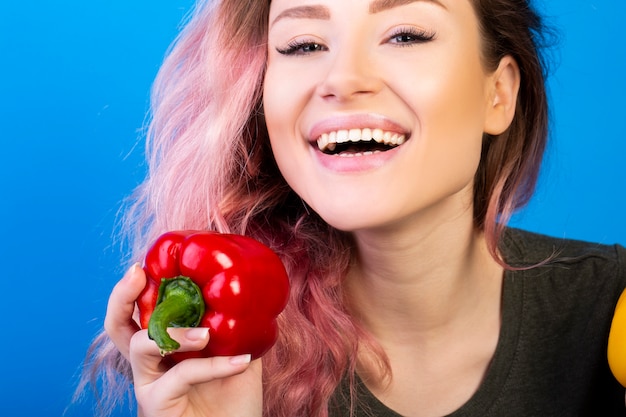 Gelukkig lachende vrouw houdt een rode peper in haar rechterhand