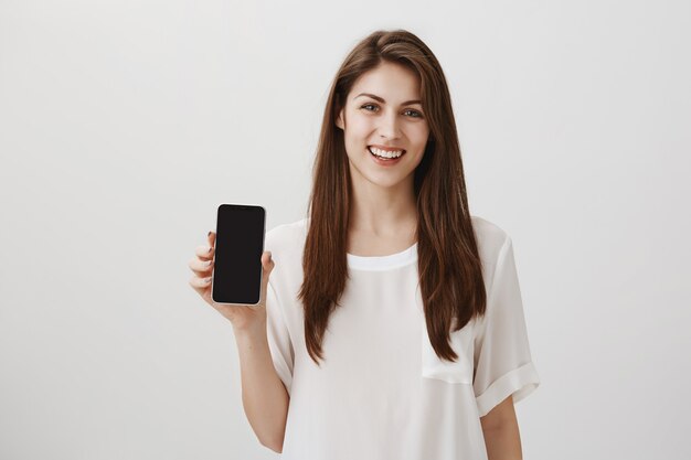 Gelukkig lachende vrouw met mobiel scherm, app of winkelsite aanbevelen